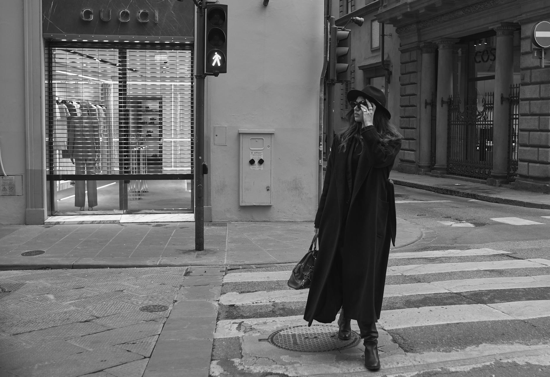 Elegancka kobieta w czerni przechodzi przez ulicę we Florencji obok Gucci