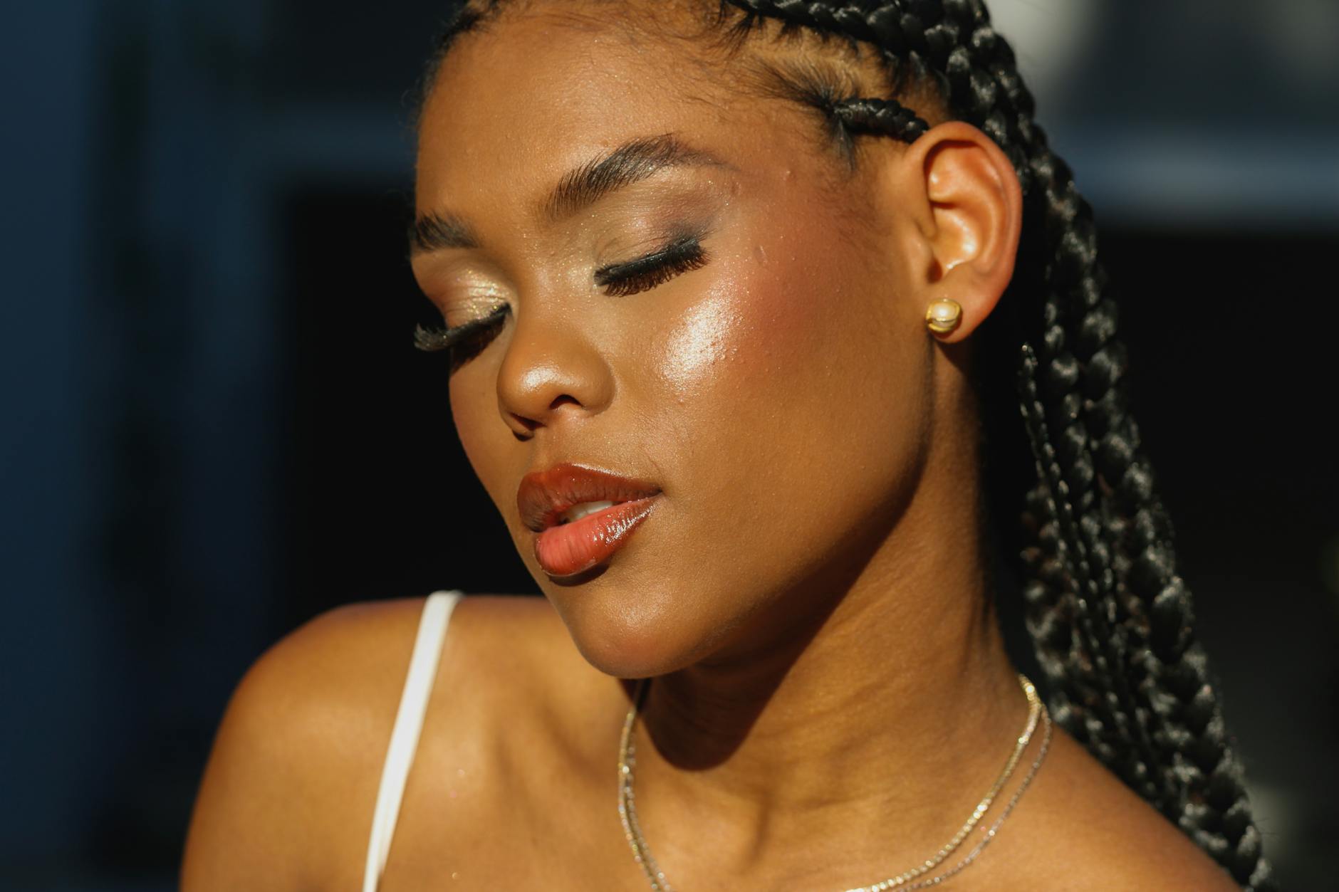 Kobieta z warkoczykami w ostrym świetle, z makijażem podkreślającym skórę