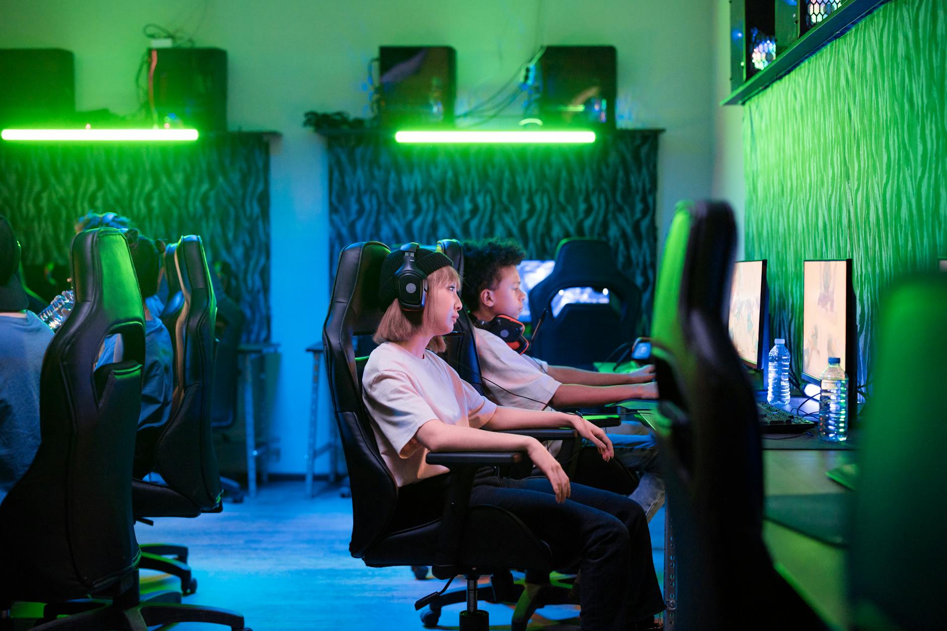 Nastolatki grające wspólnie w gry MMO w neonowo oświetlonym pokoju