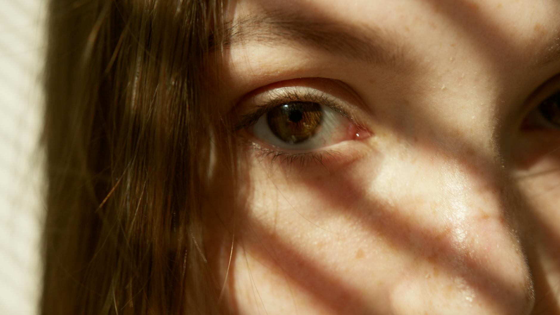 Zbliżenie oka kobiety w słońcu podkreślającym piegi i naturalny glow