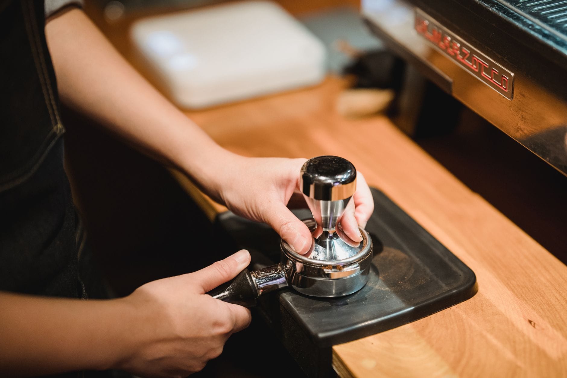 Barista ubija zmieloną kawę w kolbie do espresso w przytulnej kawiarni