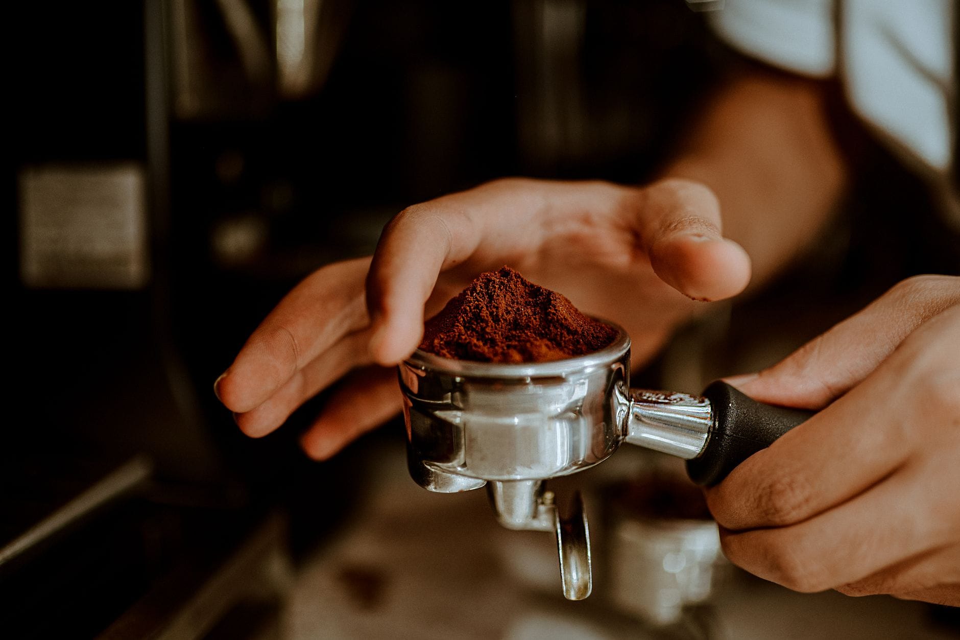Barista wsypuje świeżo zmieloną kawę do kolby do espresso
