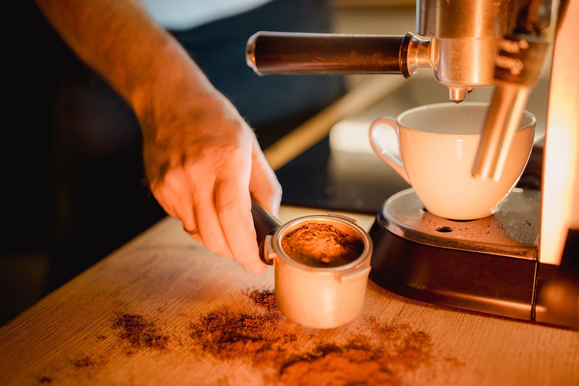 Dłoń baristy przygotowuje espresso, ubijając kawę w kolbie