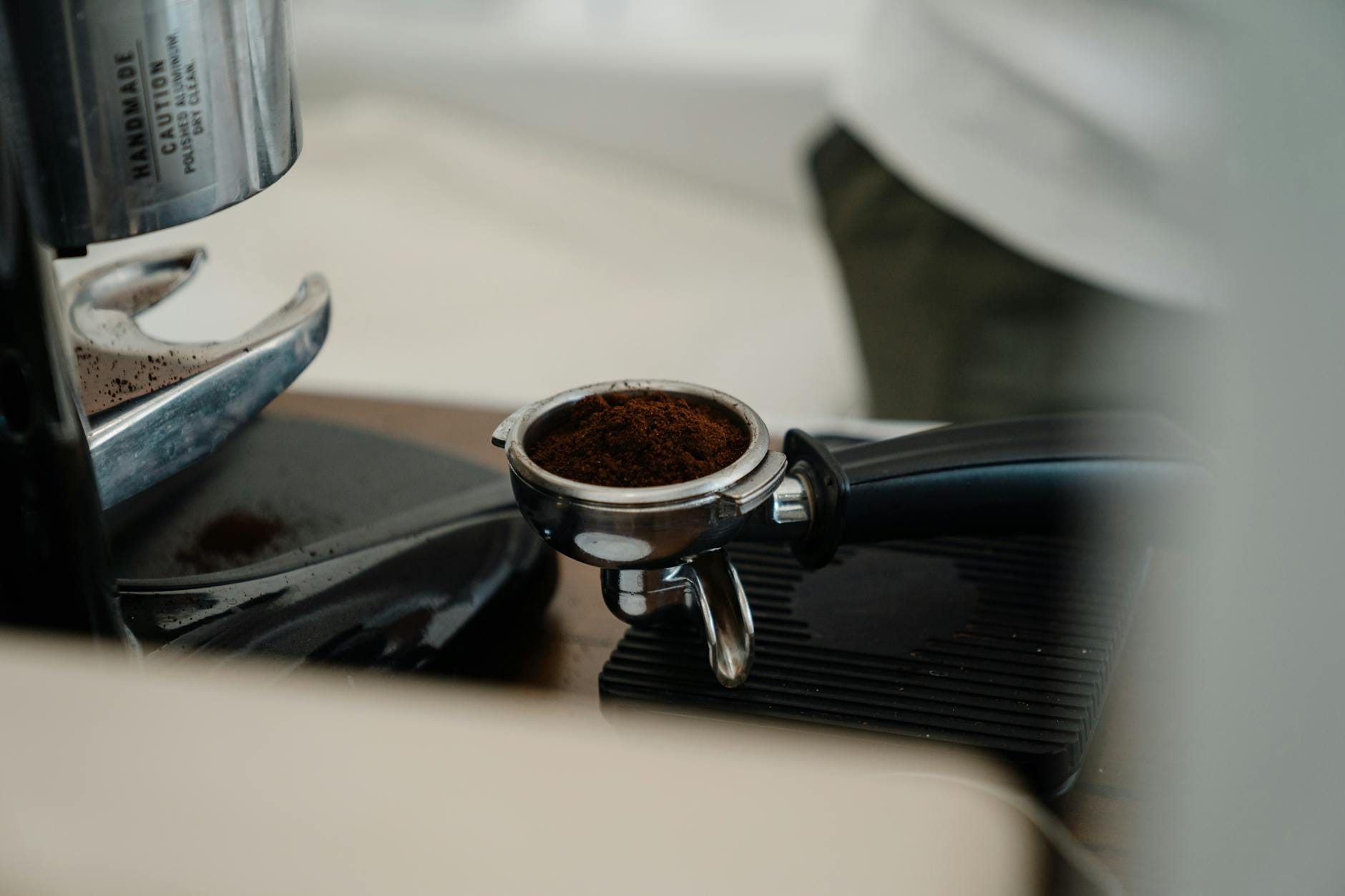 Portafilter z mieloną kawą wpięty w kolbę ekspresu w nowoczesnej kawiarni
