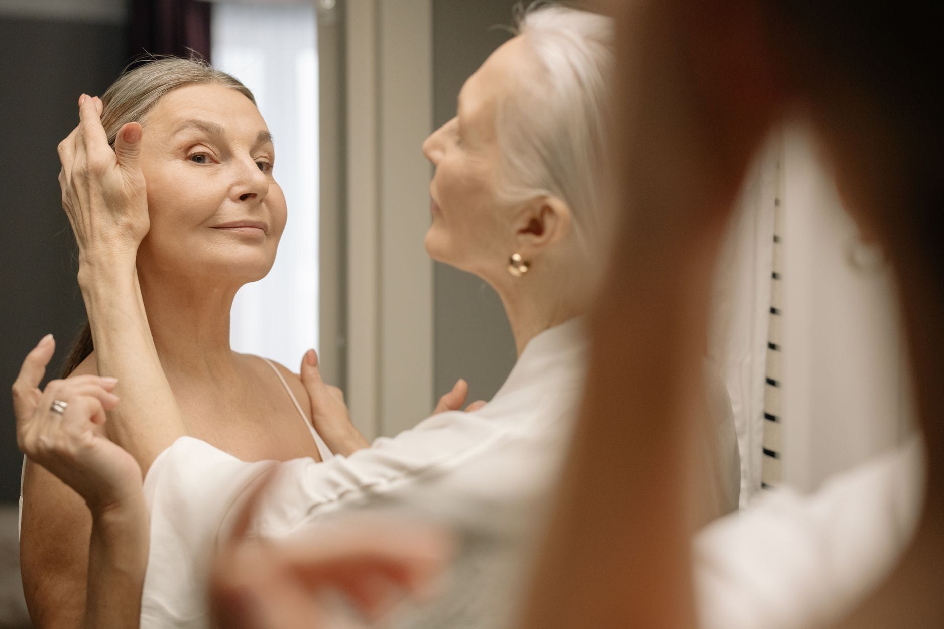 Elegancka dojrzała kobieta nakłada makijaż dzienny przed lustrem